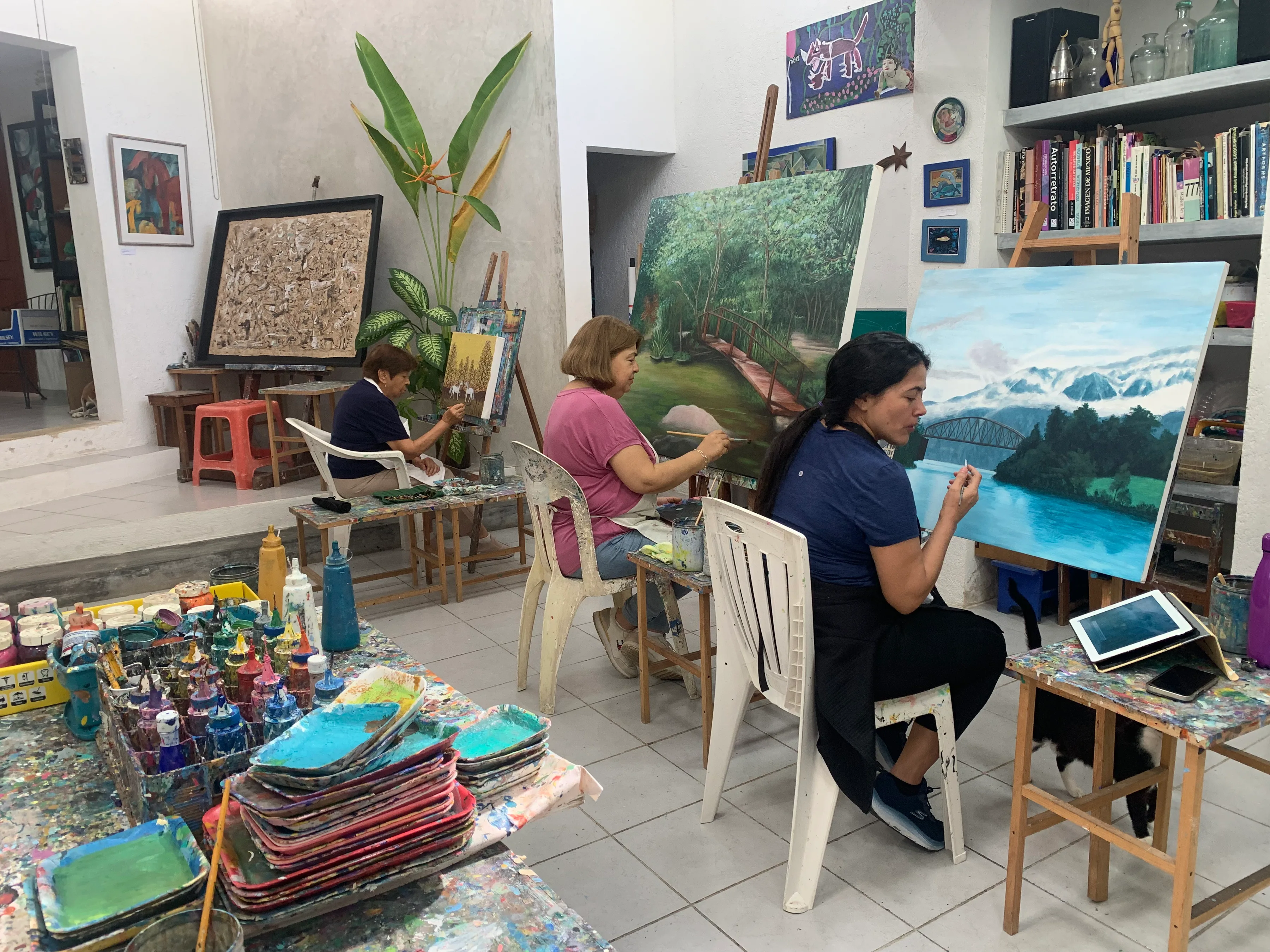 Alumnos adultos pintando en caballetes en el taller